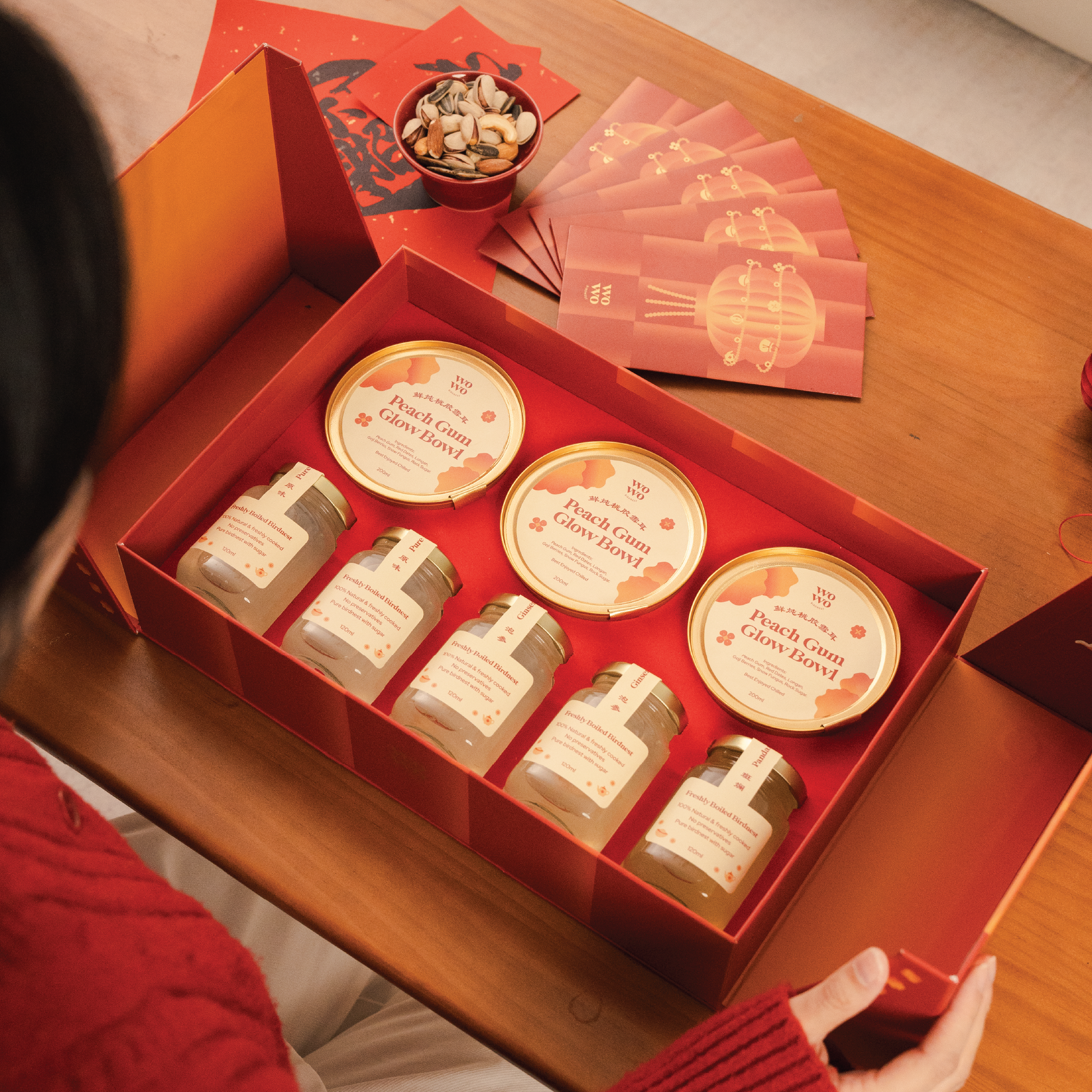 Red gift box with small jars and red envelopes on a wooden table