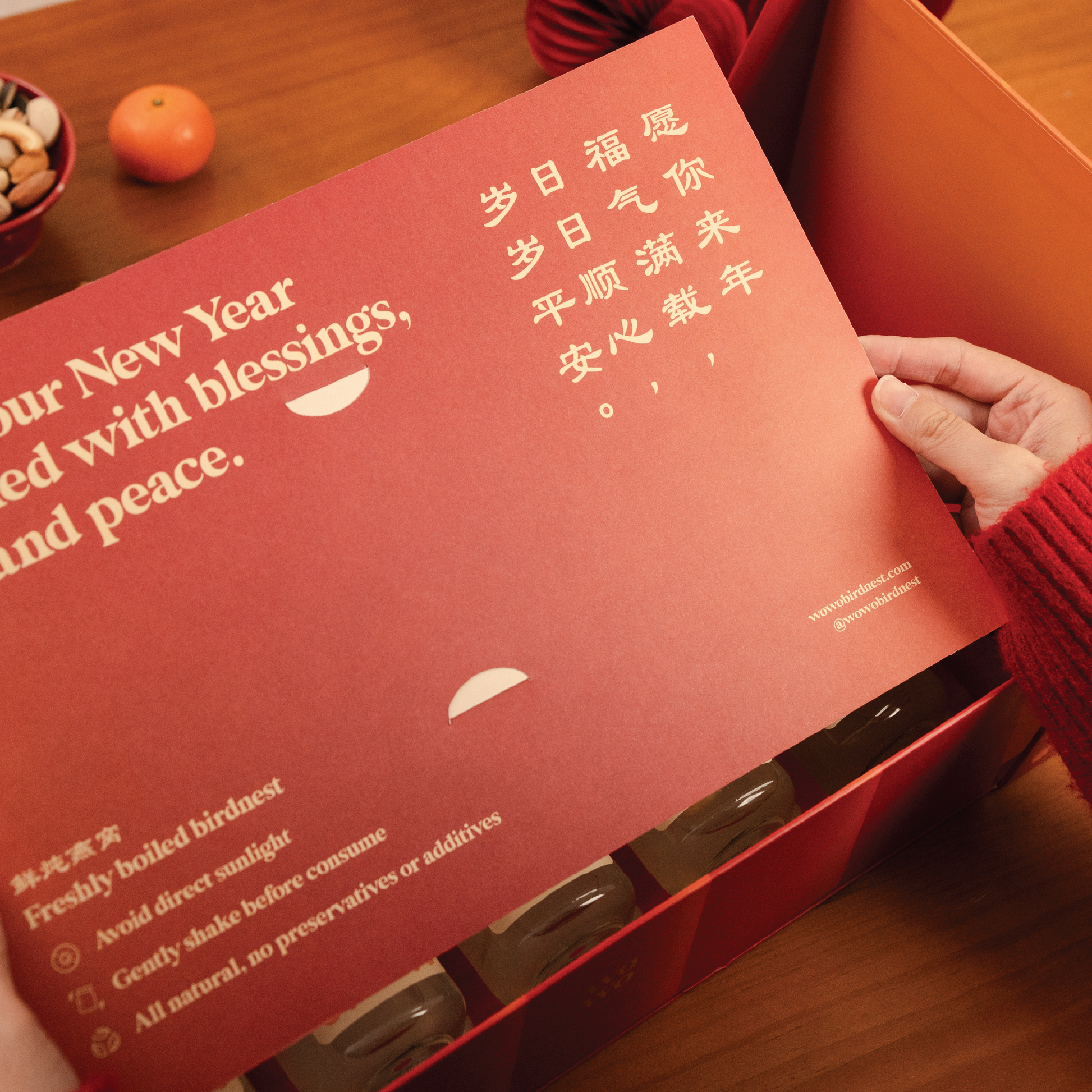 Red product packaging with text, held by a hand on a wooden surface.